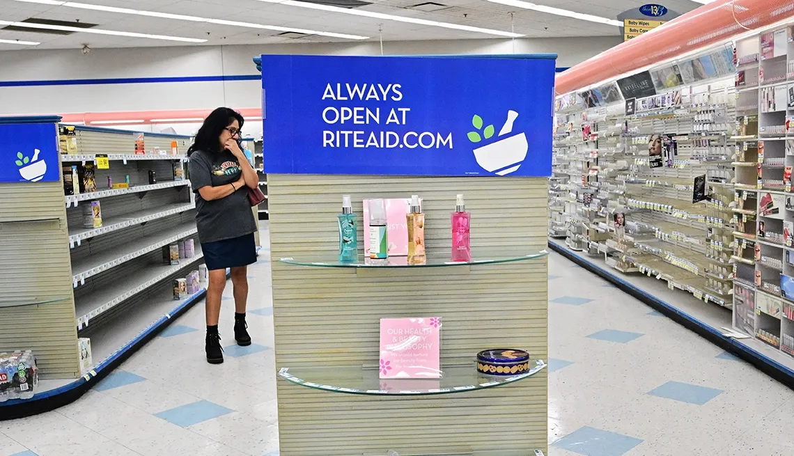 A nearly empty Rite Aid store with bare shelves and a sign directing shoppers to RiteAid.com.