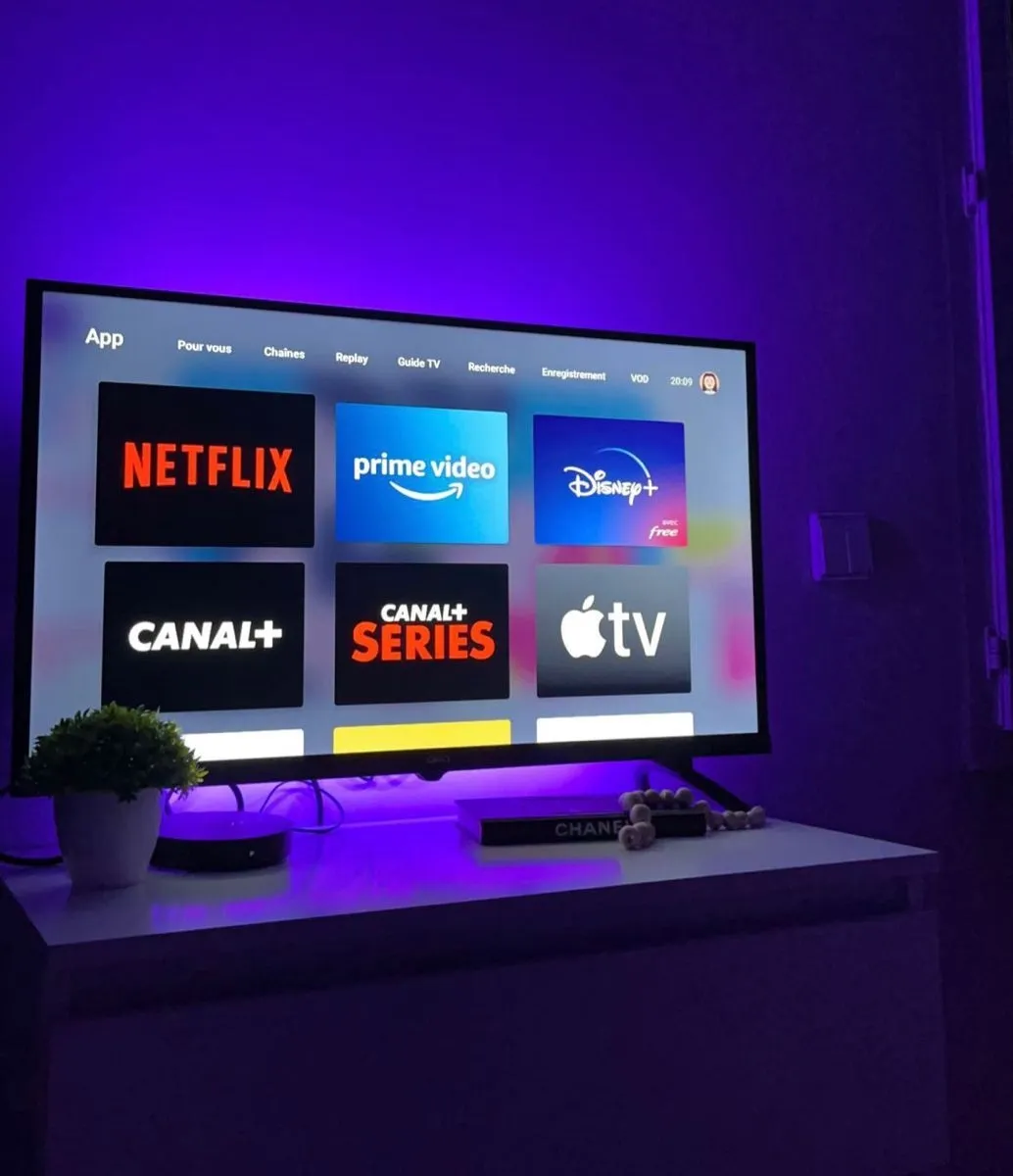 A smart TV in a dark room displays streaming service apps, lit by a purple glow. (Image: Chion Justine)