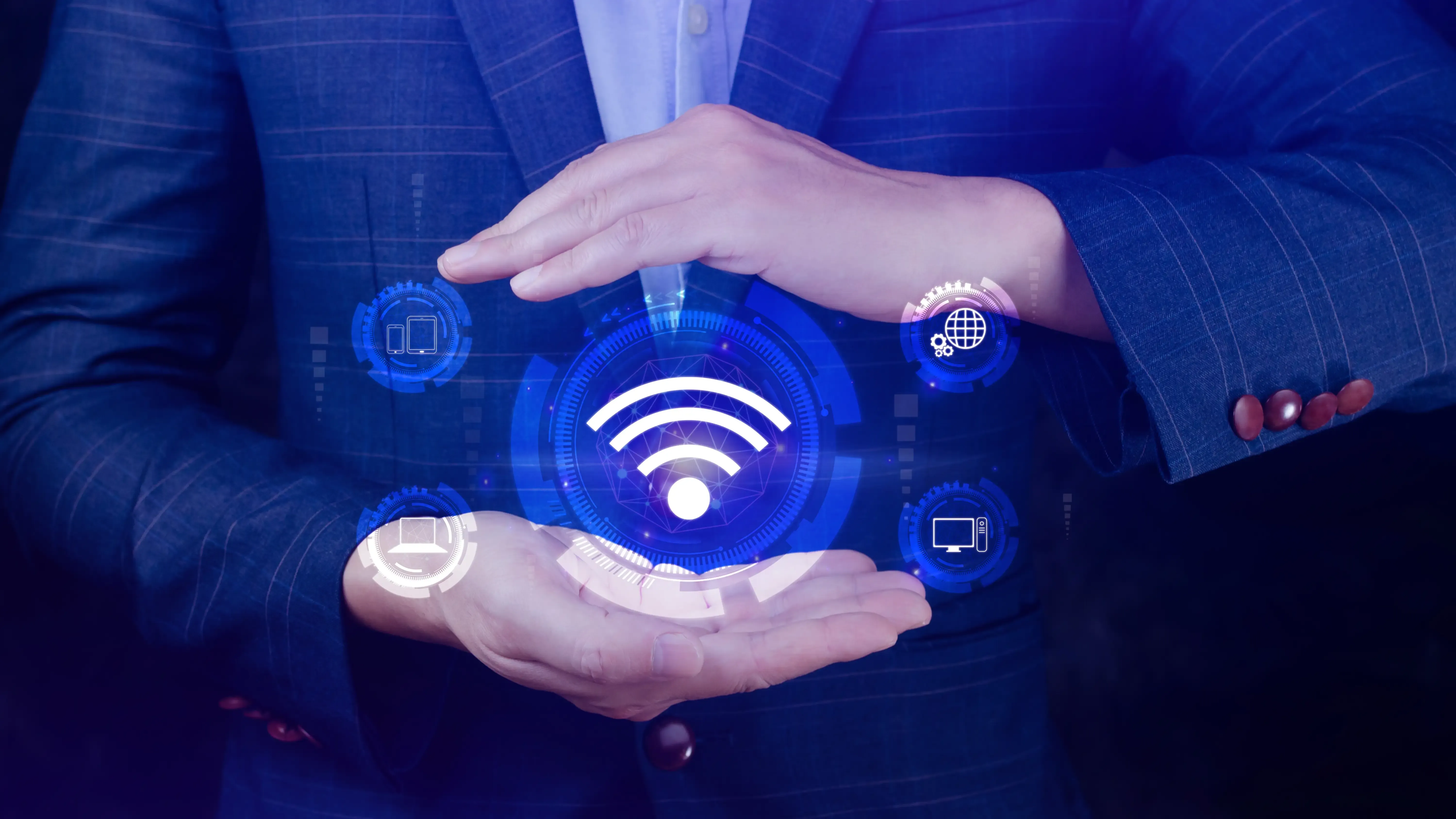 A person holds their hands around a glowing, holographic Wi-Fi symbol and connected tech icons.