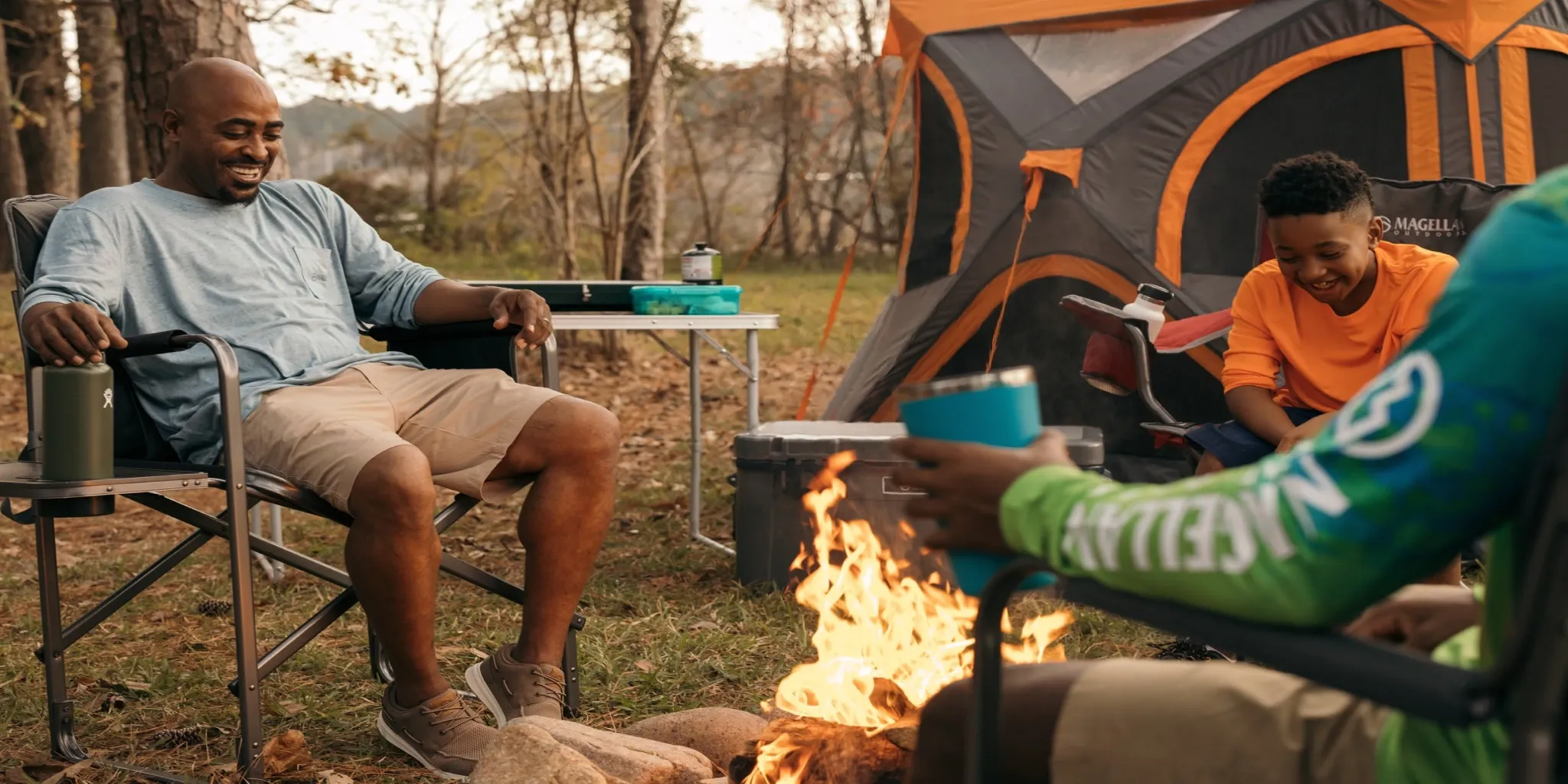A family enjoys a cozy campfire using Academy’s Magellan Outdoors gear, from the tent to the chairs.