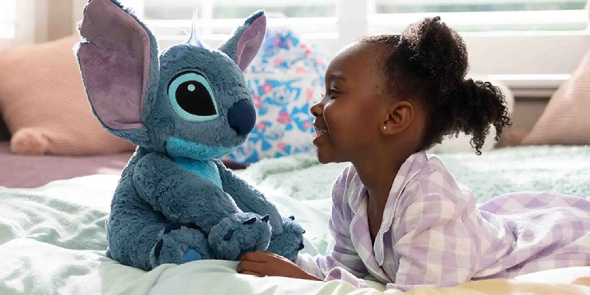 Young girl looking happily at her Disney Stitch stuffed