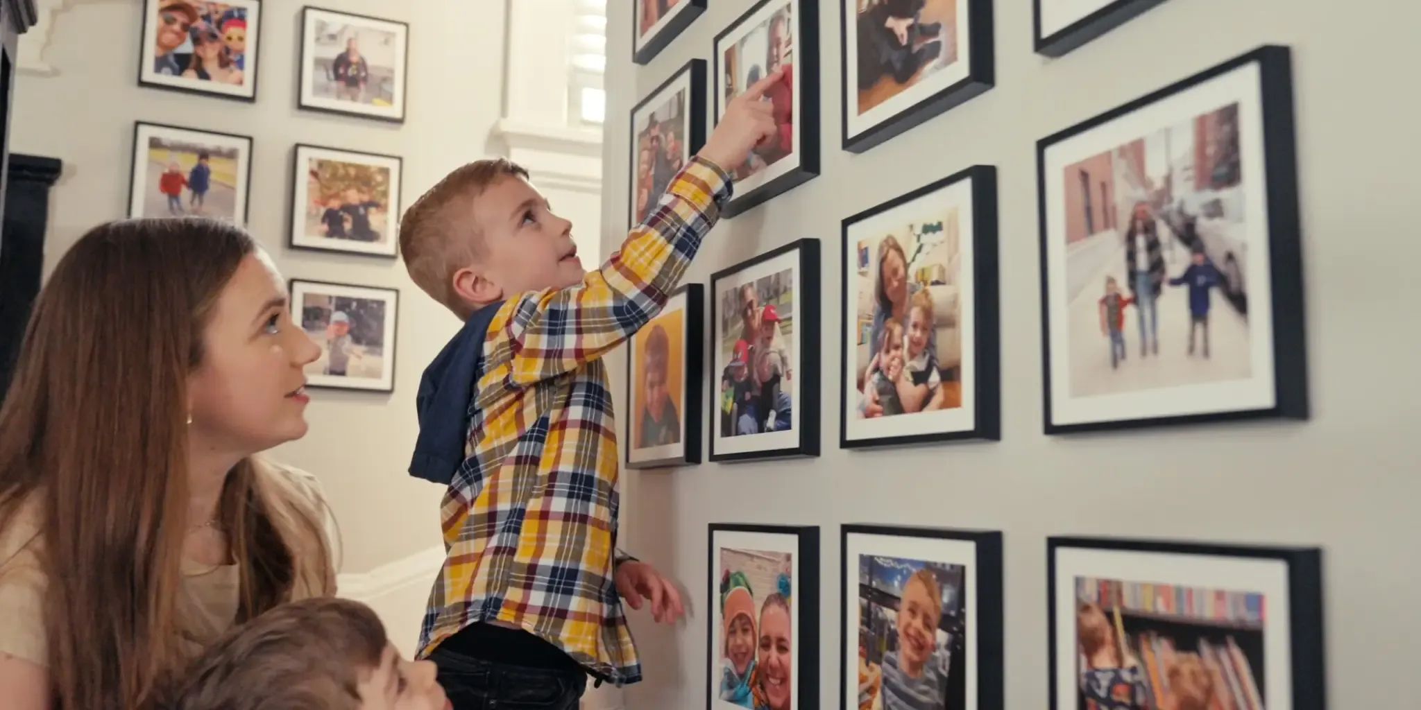 A boy pointing to a Mixtiles photo while his family watches. A boy pointing to a Mixtiles photo while his family watches.