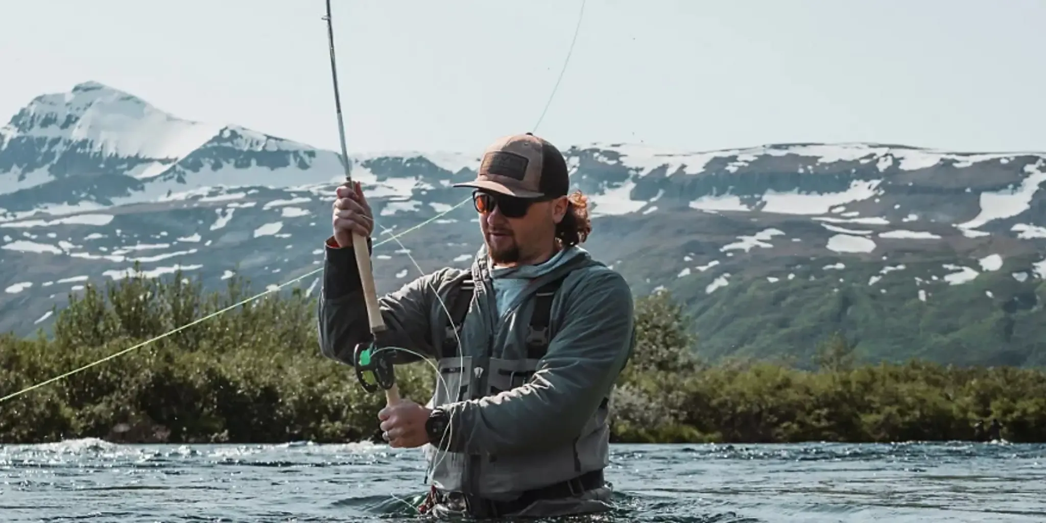 A man wearing Orvis clothing while fly-fishing in a river